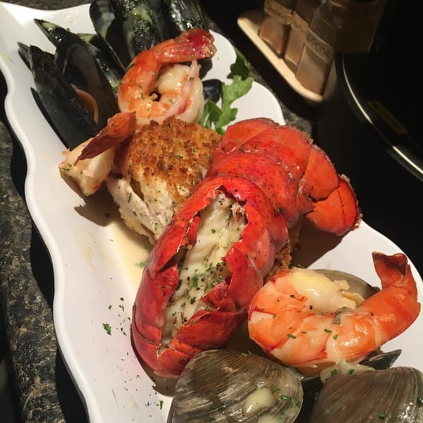 A white platter of Monticello's seafood, including lobster, shrimp, mussels, and clams.