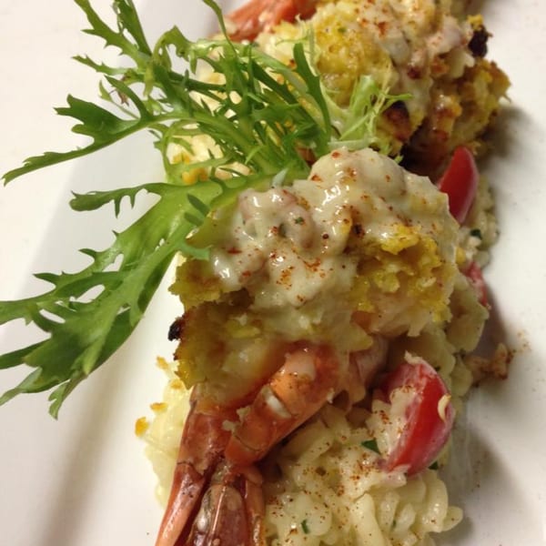 Close-up of Monticello's Italian shrimp dish with creamy sauce, cherry tomatoes, and greens.