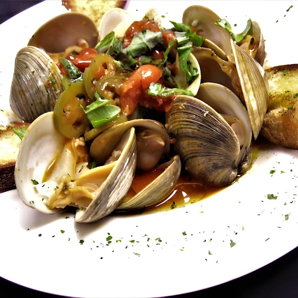 Steamed clams in a savory broth with chopped tomatoes, green peppers, and fresh basil, served with toasted bread.