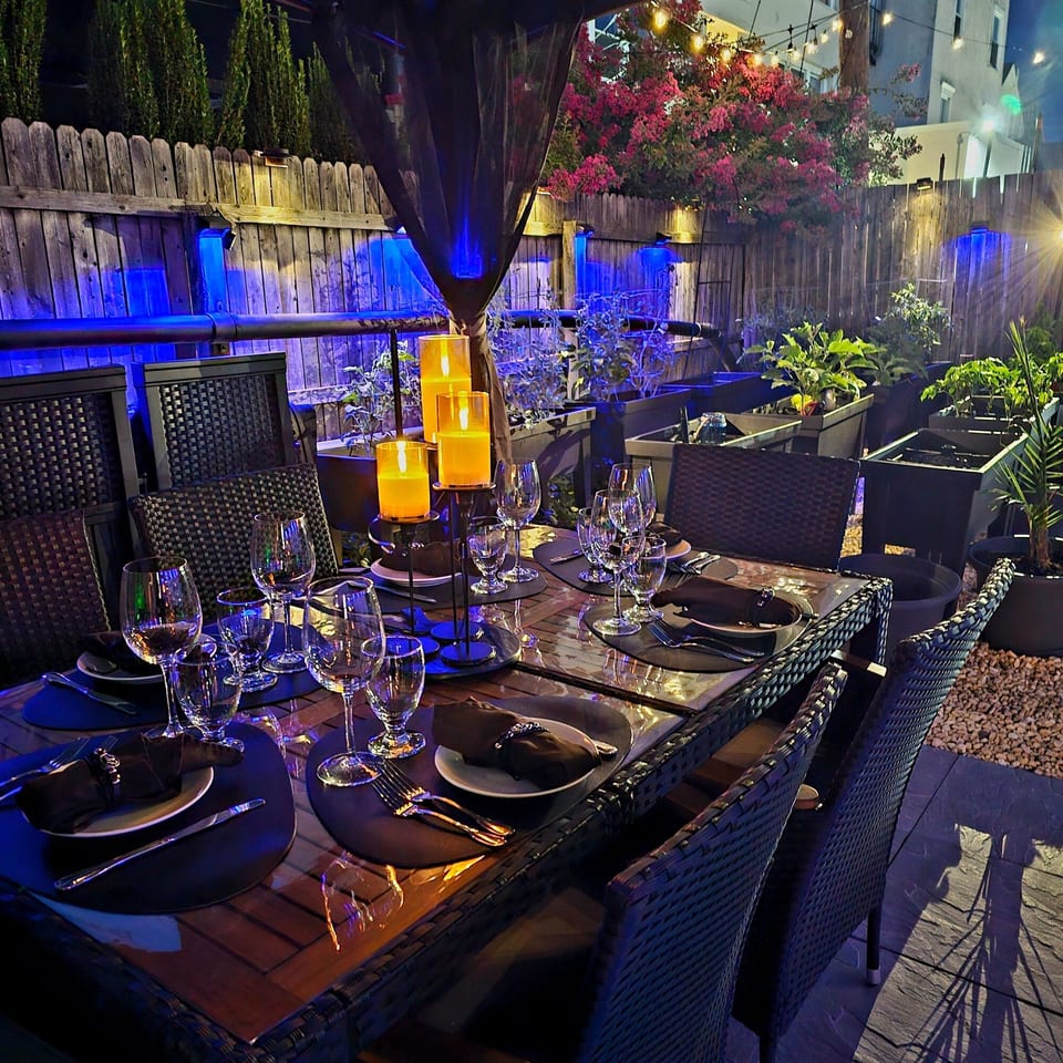 An outdoor dining table set for a Monticello Italian Restaurant dinner with candles and blue lighting.